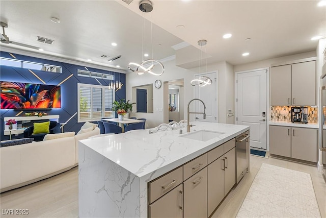 kitchen with a sink, open floor plan, gray cabinetry, recessed lighting, and hanging light fixtures