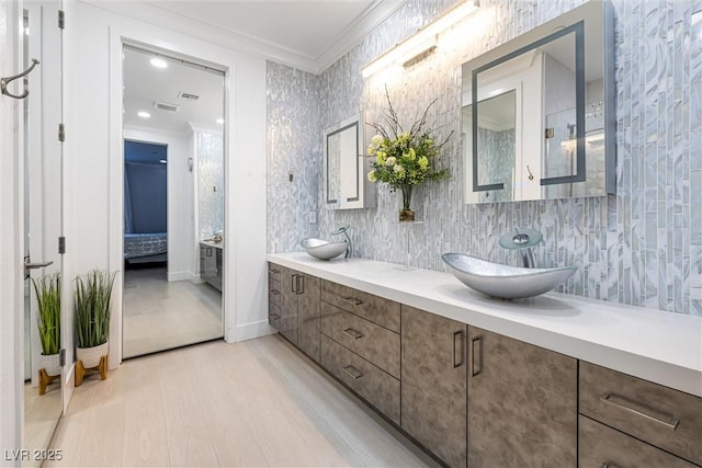 bathroom featuring crown molding, wood finished floors, ensuite bath, and double vanity