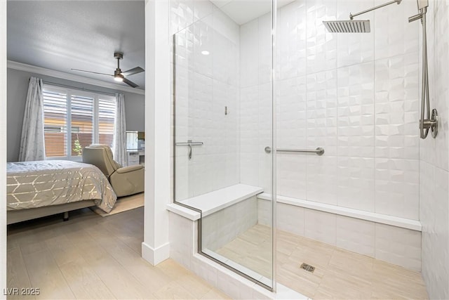ensuite bathroom with ceiling fan, a shower stall, wood finished floors, and ornamental molding