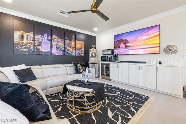 living room with crown molding, wine cooler, ceiling fan, recessed lighting, and light wood-type flooring