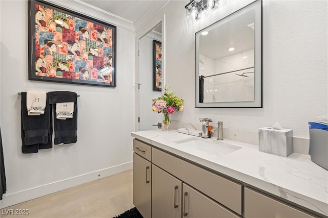 bathroom with wood finished floors, baseboards, a shower, vanity, and ornamental molding