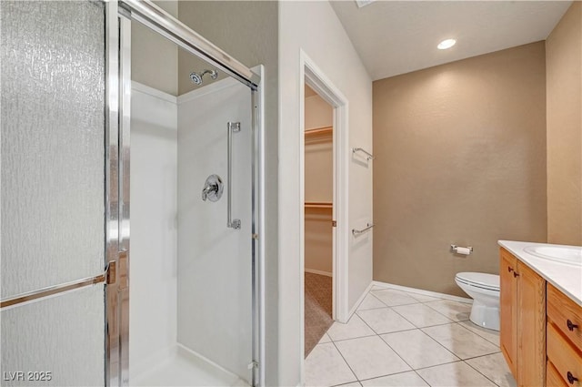 full bath featuring a stall shower, vanity, a spacious closet, tile patterned floors, and toilet