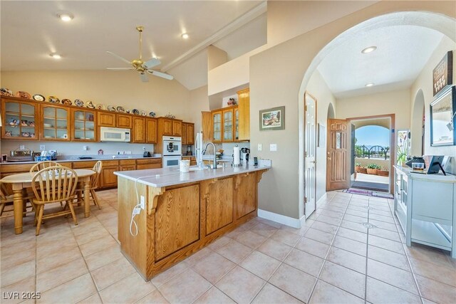 3640 E Vineyard Dr, Pahrump, NV 89048 - kitchen featuring white appliances, arched walkways, brown cabinetry, a peninsula, and ceiling fan