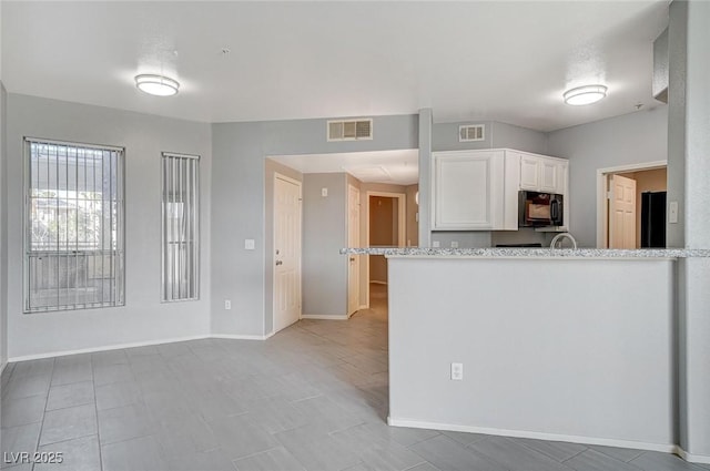 kitchen featuring black appliances, white cabinetry, baseboards, light tile patterned flooring, and light stone countertops