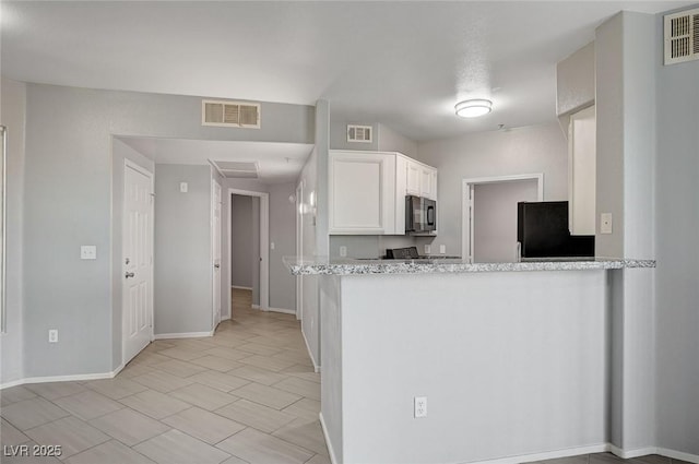 7189 S Durango Dr Unit 208, Las Vegas, NV 89113 - kitchen with black microwave, freestanding refrigerator, white cabinets, baseboards, and a peninsula
