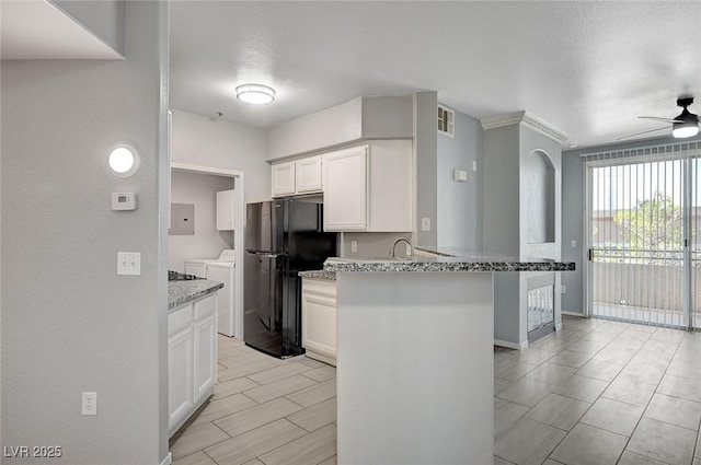 7189 S Durango Dr Unit 208, Las Vegas, NV 89113 - kitchen featuring washer and dryer, freestanding refrigerator, a peninsula, white cabinets, and light stone counters
