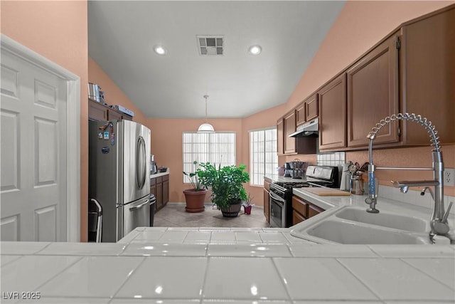 608 Blooming View Ave, North Las Vegas, NV 89032 - kitchen featuring appliances with stainless steel finishes, a sink, vaulted ceiling, light tile patterned floors, and tile countertops