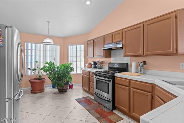 608 Blooming View Ave, North Las Vegas, NV 89032 - kitchen featuring appliances with stainless steel finishes, under cabinet range hood, tile countertops, hanging light fixtures, and light tile patterned flooring