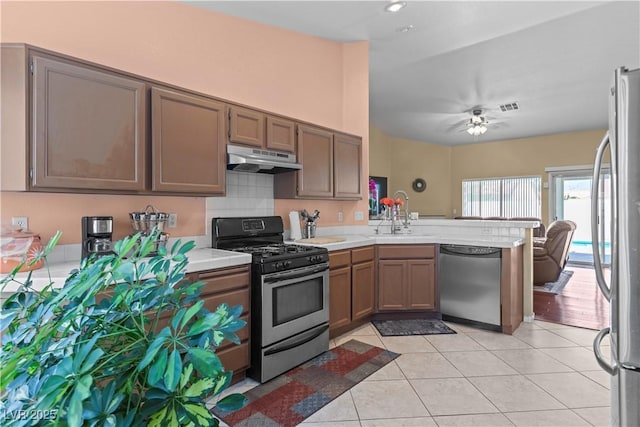 608 Blooming View Ave, North Las Vegas, NV 89032 - kitchen with appliances with stainless steel finishes, a peninsula, under cabinet range hood, light countertops, and light tile patterned floors