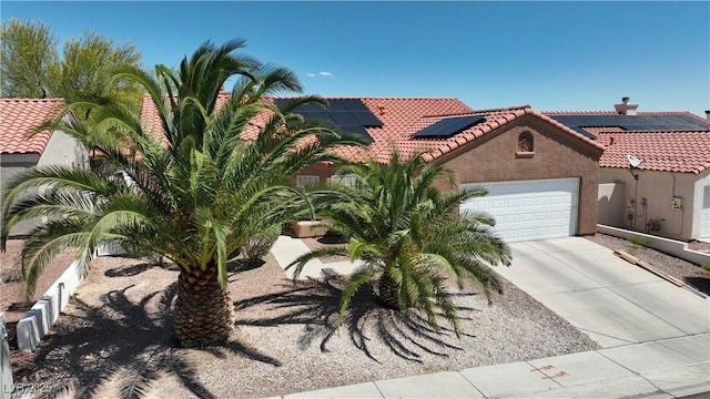 608 Blooming View Ave, North Las Vegas, NV 89032 - view of front facade featuring a tiled roof, an attached garage, roof mounted solar panels, stucco siding, and concrete driveway