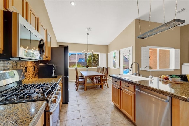kitchen with stainless steel appliances, a sink, backsplash, light tile patterned floors, and a chandelier