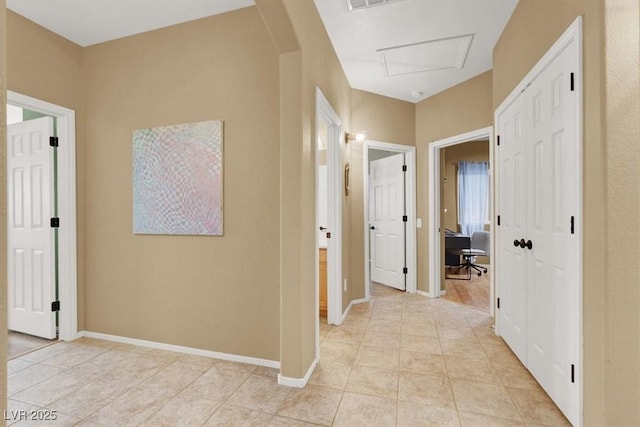 hallway featuring a desk, light tile patterned floors, and baseboards