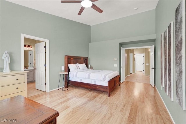 bedroom with light wood-style flooring, baseboards, connected bathroom, and a ceiling fan