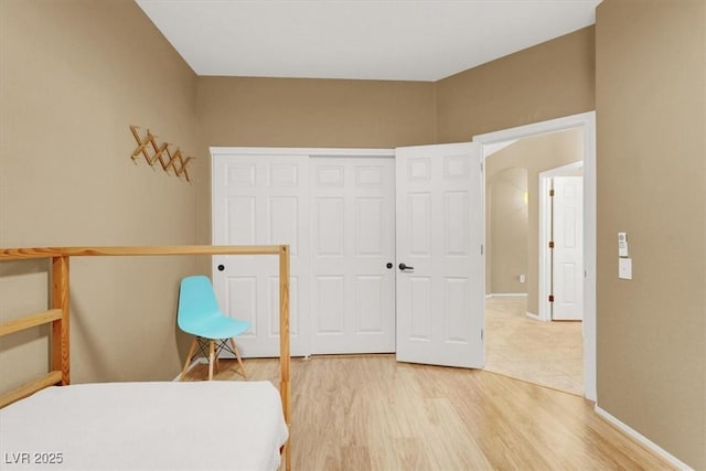 bedroom with light wood-style flooring, a closet, and baseboards