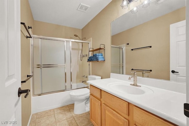 bathroom with toilet, vanity, tile patterned flooring, and bath / shower combo with glass door
