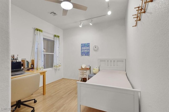 bedroom featuring wood finished floors, a desk, and rail lighting