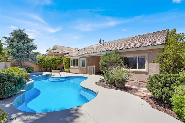view of pool with fence, a patio area, and a pool with connected hot tub