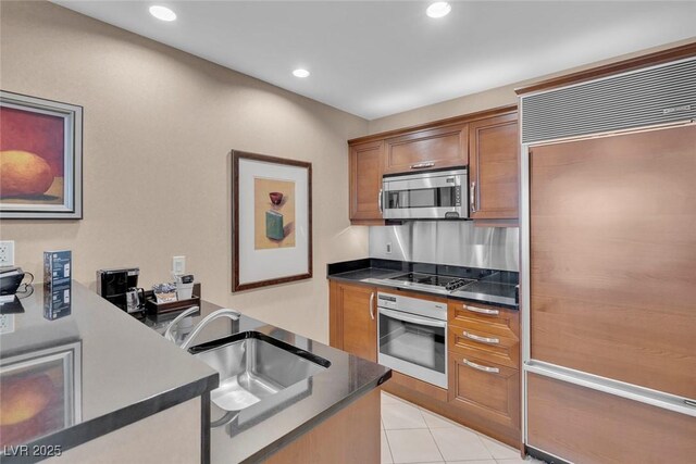 135 E Harmon Ave Unit 1102, Las Vegas, NV 89109 - kitchen with wall oven, stainless steel microwave, paneled built in refrigerator, brown cabinetry, and black electric cooktop
