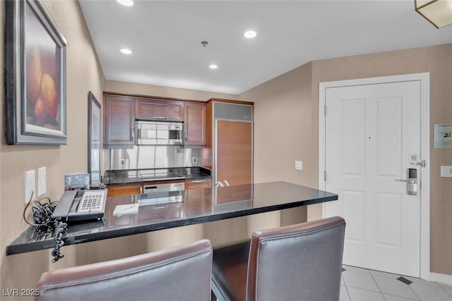 135 E Harmon Ave Unit 1102, Las Vegas, NV 89109 - kitchen with stainless steel microwave, a peninsula, recessed lighting, light tile patterned flooring, and a breakfast bar area