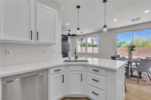 kitchen featuring dishwasher, a sink, a peninsula, recessed lighting, and white cabinets
