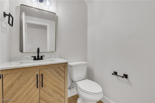 bathroom with baseboards, toilet, and vanity