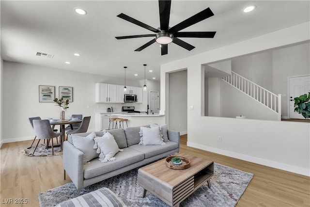 living room featuring recessed lighting, a ceiling fan, light wood-style floors, baseboards, and stairway
