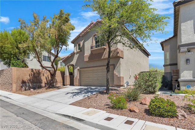 mediterranean / spanish home with an attached garage, stucco siding, fence, and concrete driveway