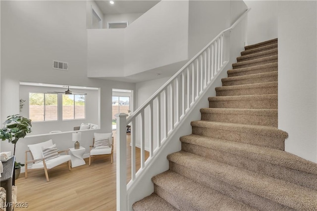 stairs featuring wood finished floors, a towering ceiling, and baseboards