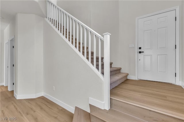entryway featuring wood finished floors, baseboards, and stairway