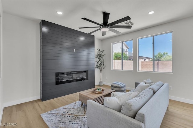 living area with baseboards, ceiling fan, recessed lighting, wood finished floors, and a fireplace