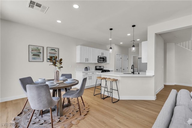 dining area featuring baseboards, light wood-type flooring, and recessed lighting