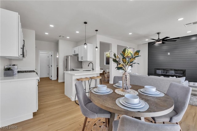 dining space with light wood-style flooring, a ceiling fan, recessed lighting, and baseboards