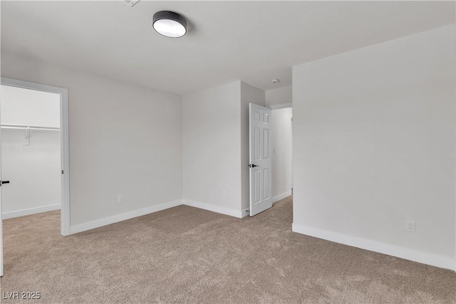 unfurnished bedroom featuring carpet flooring, baseboards, a walk in closet, and a closet