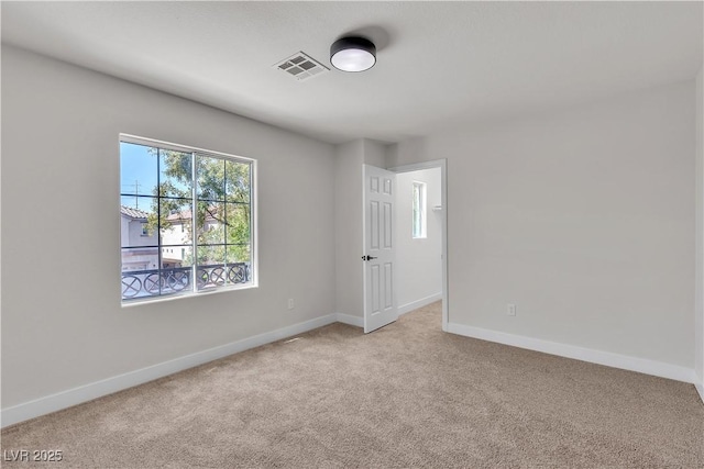 spare room with light colored carpet and baseboards