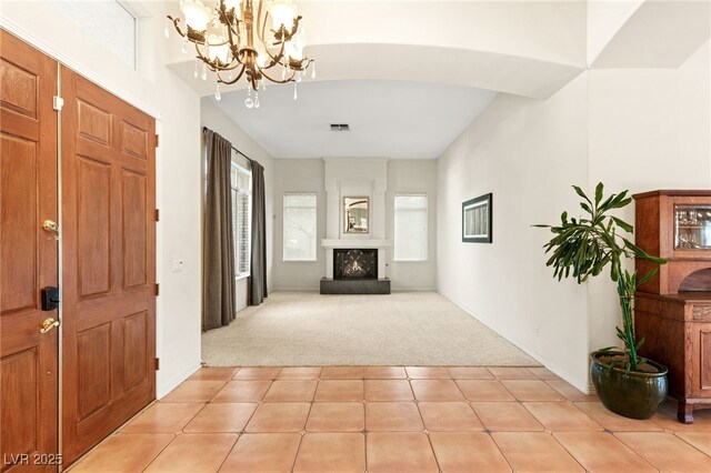 4649 Bird View Ct, Las Vegas, NV 89129 - entrance foyer with light colored carpet, a chandelier, a lit fireplace, and light tile patterned flooring