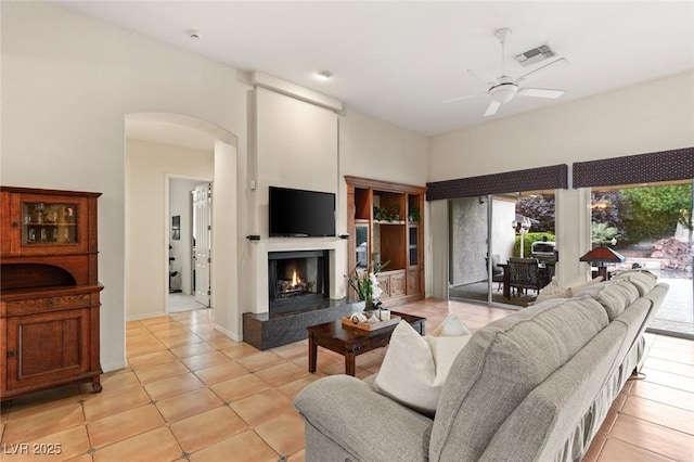 4649 Bird View Ct, Las Vegas, NV 89129 - living room with arched walkways, a ceiling fan, light tile patterned floors, a premium fireplace, and baseboards