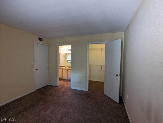555 E Silverado Ranch Blvd Unit 2147, Las Vegas, NV 89183 - unfurnished bedroom with dark colored carpet, a spacious closet, baseboards, a closet, and ensuite bathroom