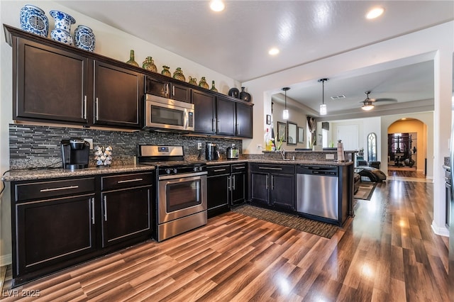184 Cullerton St, Las Vegas, NV 89148 - kitchen featuring stainless steel appliances, dark wood finished floors, backsplash, a peninsula, and arched walkways