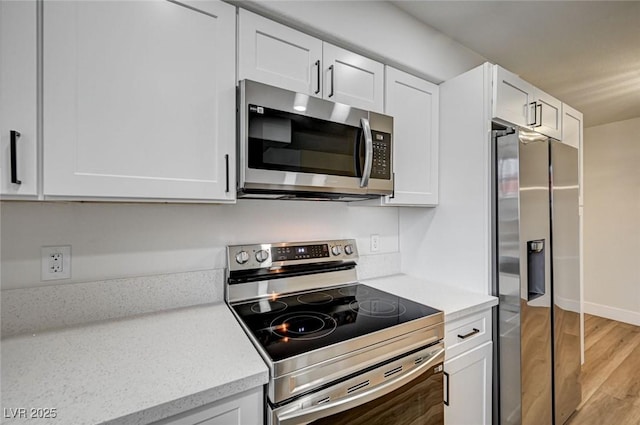 2725 S Nellis Blvd Unit 2036, Las Vegas, NV 89121 - kitchen with stainless steel appliances, light wood finished floors, white cabinetry, and light stone countertops
