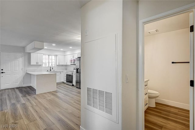 2725 S Nellis Blvd Unit 2036, Las Vegas, NV 89121 - kitchen featuring appliances with stainless steel finishes, light wood-style flooring, white cabinetry, a sink, and light countertops