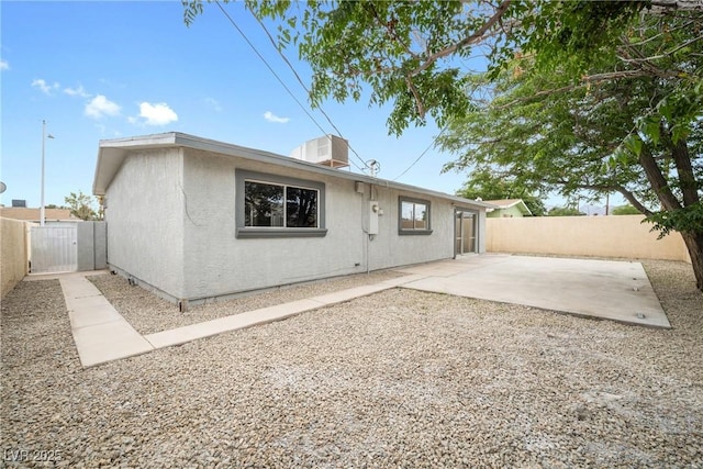 back of property with a fenced backyard, a patio, and a gate