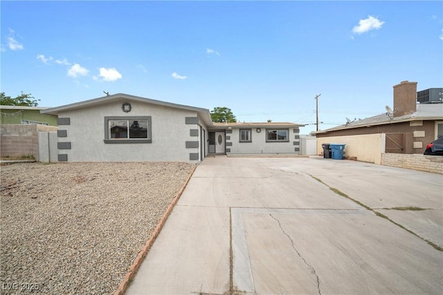 view of front of home with central AC, concrete driveway, fence, and stucco siding