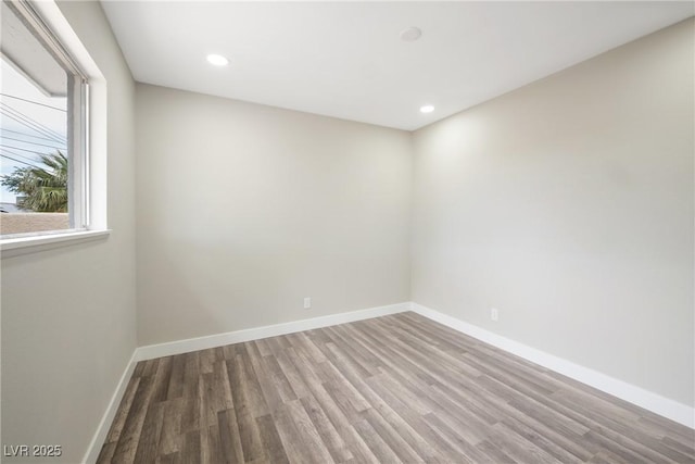 empty room with wood finished floors, baseboards, and recessed lighting