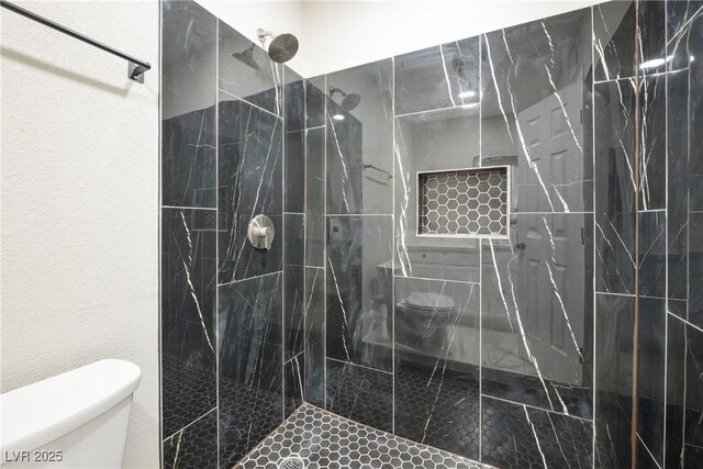 bathroom with toilet and a marble finish shower