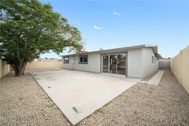 rear view of house with a fenced backyard, a patio, and stucco siding