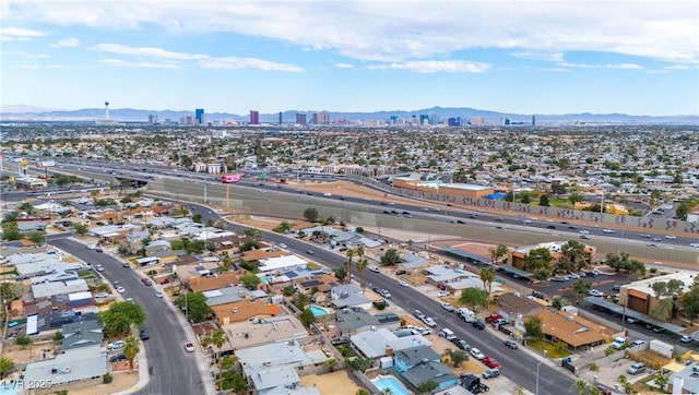 aerial view of property and surrounding area with a mountainous background, nearby urban area, and a main thoroughfare