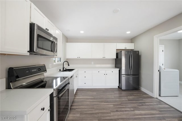 kitchen featuring stainless steel appliances, washer / clothes dryer, dark wood finished floors, a sink, and recessed lighting