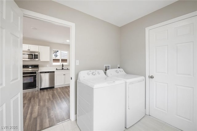 washroom with washer and clothes dryer and light wood finished floors
