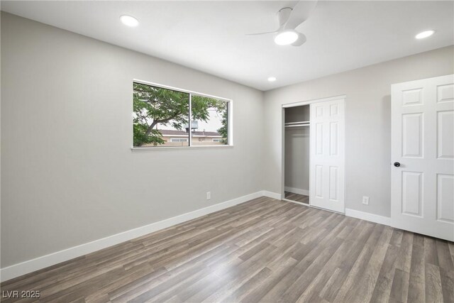 unfurnished bedroom with wood finished floors, baseboards, a closet, recessed lighting, and a ceiling fan