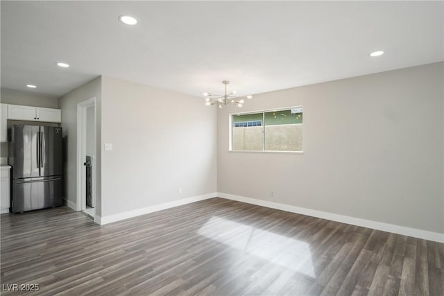 empty room featuring dark wood-type flooring, baseboards, a chandelier, and recessed lighting